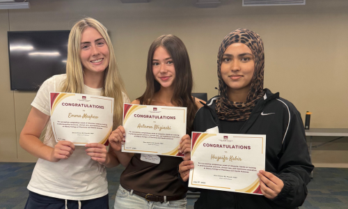 Three girls hold up a certificate